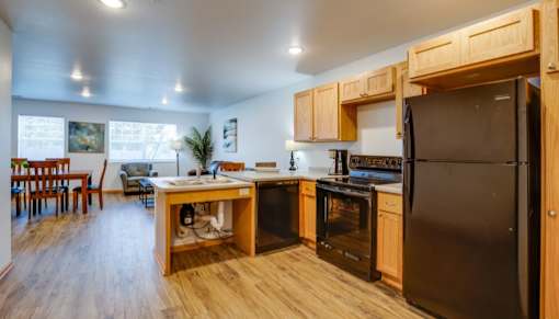 A kitchen with wooden cabinets and a black refrigerator.