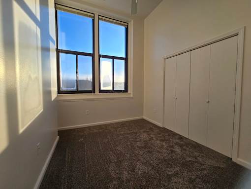 A room with a large window and a carpeted floor.
