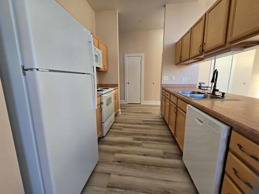 A kitchen with a white refrigerator and wooden floors.