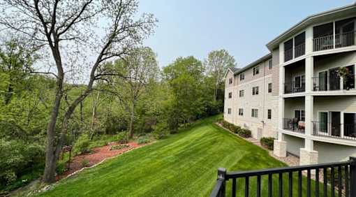 Apartment complex with a green lawn and trees in the background.