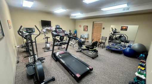 A room full of exercise equipment including treadmills, stationary bikes, and weights.