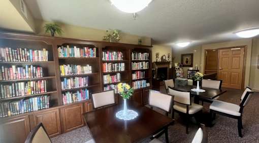 A room with a table, chairs, and bookshelves filled with books.