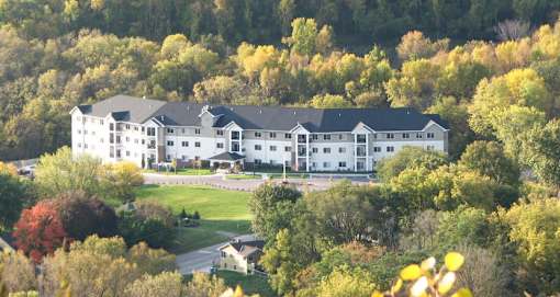 A large white building surrounded by trees in autumn.
