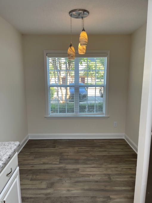 A breakfast nook with three hanging lights and a large window.