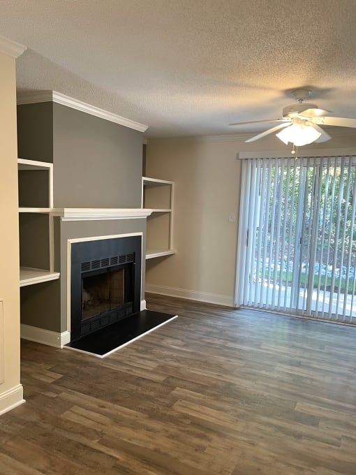 An unfurnished living room with a fireplace and a sliding glass door.