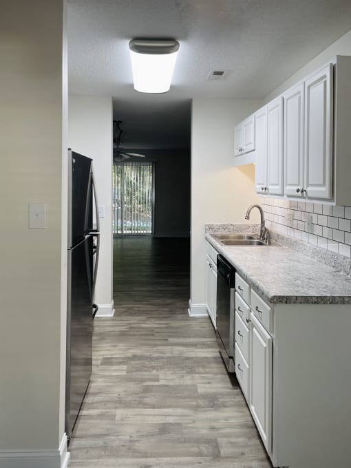 A kitchen with white cabinets and a black refrigerator.