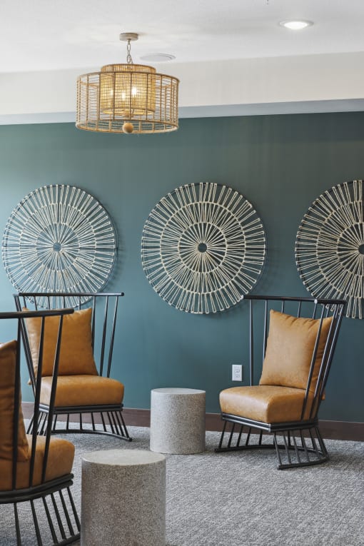 a living room with two orange chairs and two round stools in front of a green wall