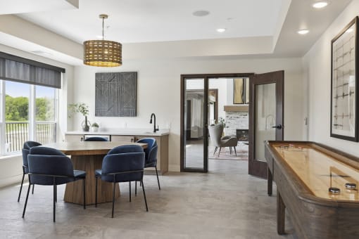 a games room with a shuffleboard table and blue chairs