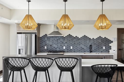 a kitchen with white walls and a large island with four black and white bar stools