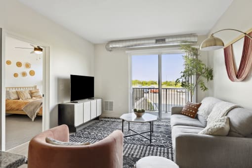 a spacious living room with a sliding glass door leading to a balcony with a view of the