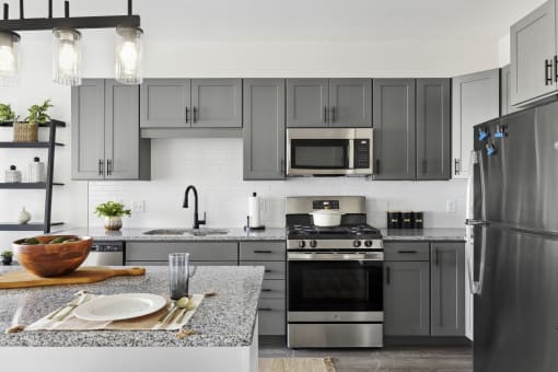 a kitchen with gray cabinets and stainless steel appliances