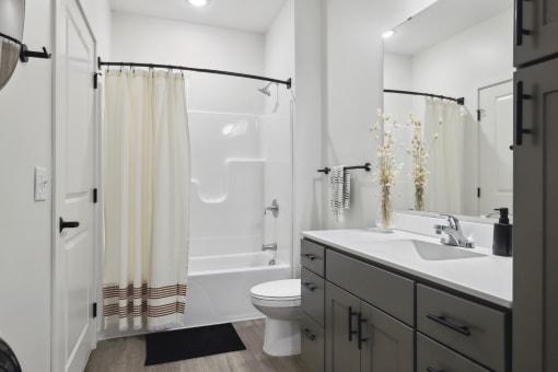 a bathroom with a white sink and toilet next to a white bathtub with a shower curtain