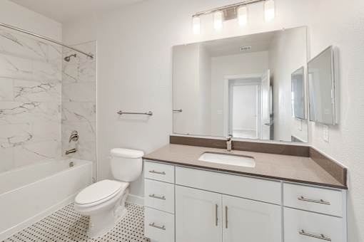 A white bathroom with a marble patterned shower.