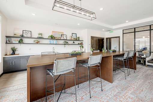 A modern kitchen with a long wooden island and four chairs.