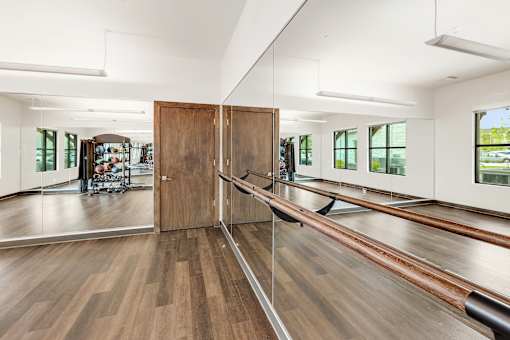 A room with a wooden floor and a mirrored wall.