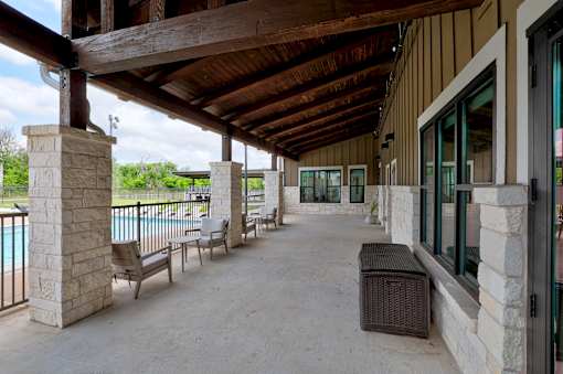 A covered patio area with a pool in the background.