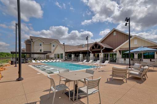 A pool area with chairs and a building in the background.