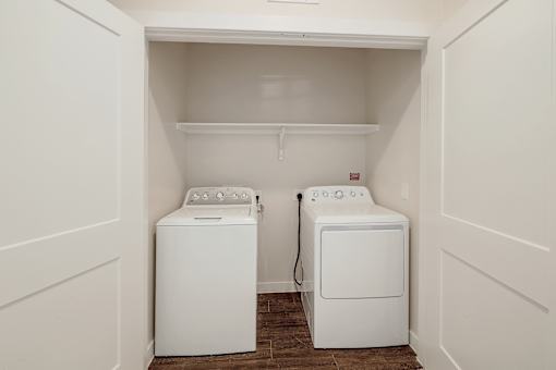 Two white front loading washing machines in a small laundry room.