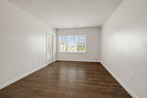 A room with wooden flooring and a window with blinds.