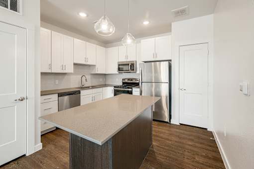 A kitchen with a stainless steel refrigerator and a wooden island.