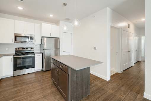 A modern kitchen with stainless steel appliances and wooden floors.