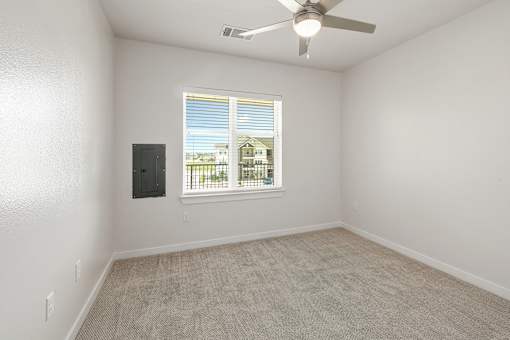 A room with a ceiling fan and a window with blinds.