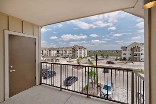 A balcony view of a residential area with cars and houses.