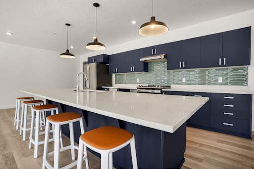 A kitchen with a white countertop and orange bar stools.