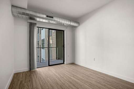 A room with a sliding glass door leading to a balcony.