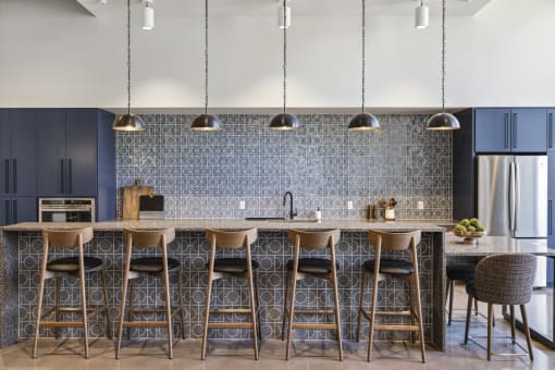 a kitchen with bar stools in front of a marble counter top and blue cabinets