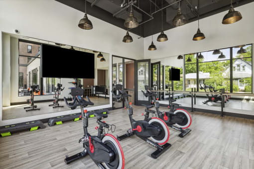 a gym with exercise bikes on the floor and a large window