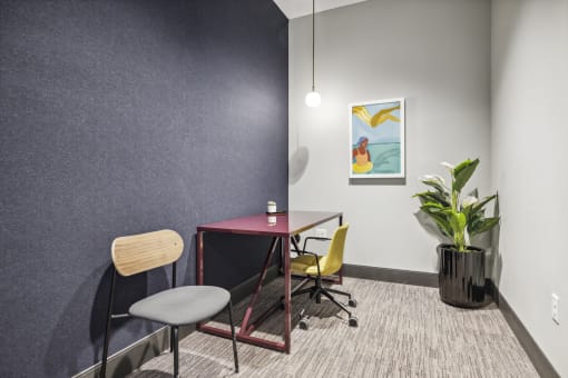 a room with a desk and chairs and a potted plant