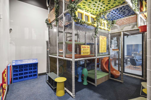 a childrens play area with a playhouse and a set of plastic chairs and