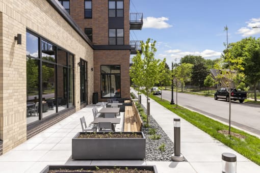 the sidewalk outside of a building with tables and benches