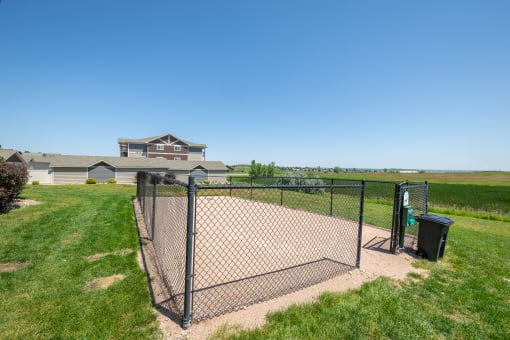 a fenced in dog park with a house in the background