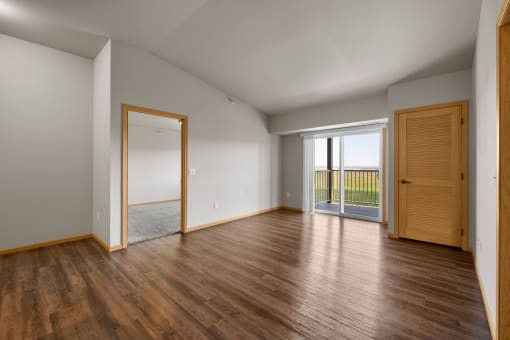 a bedroom with hardwood floors and a sliding glass door leading to a balcony