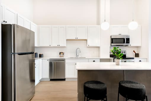 A modern kitchen with white cabinets and a stainless steel refrigerator.