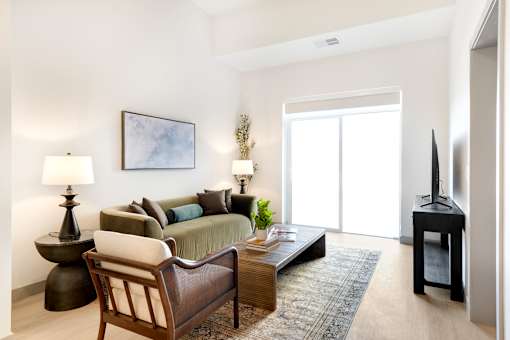 A living room with a sofa, a chair, a table, and a painting on the wall.