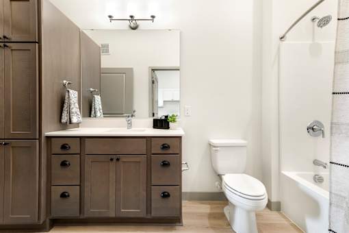 A bathroom with a white toilet, a sink with a mirror, and a shower with a white shower curtain.