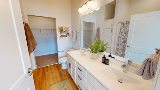 A bathroom with a white counter and a brown towel hanging on the door.