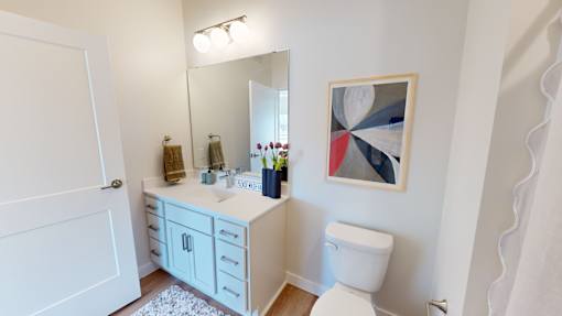 A bathroom with a white toilet, sink, and a painting on the wall.