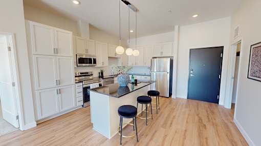 A kitchen with a bar and stools in the middle.