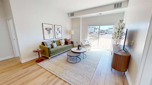 A living room with a green couch, a coffee table, and a television.