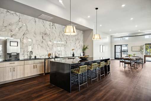 A modern kitchen with a marble backsplash and dark wood floors.