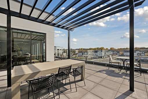 A patio with a table and chairs is covered by a roof.