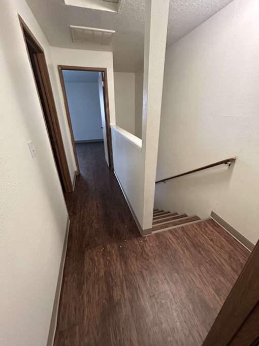 A hallway with wood flooring and white walls.