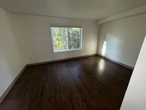 A room with wooden flooring and a window.