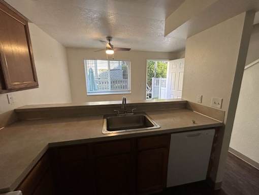 A kitchen with a brown countertop and a white dishwasher.