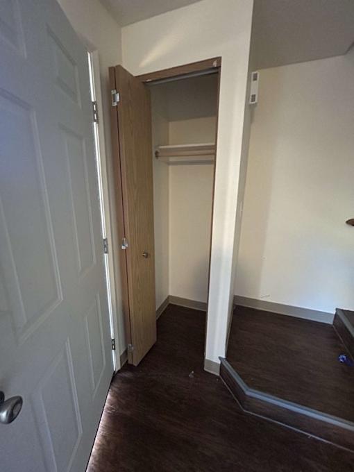 A white door is open to a hallway with a brown floor.
