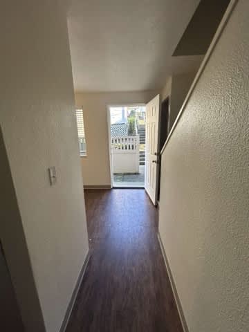A hallway with a wooden floor and white walls.